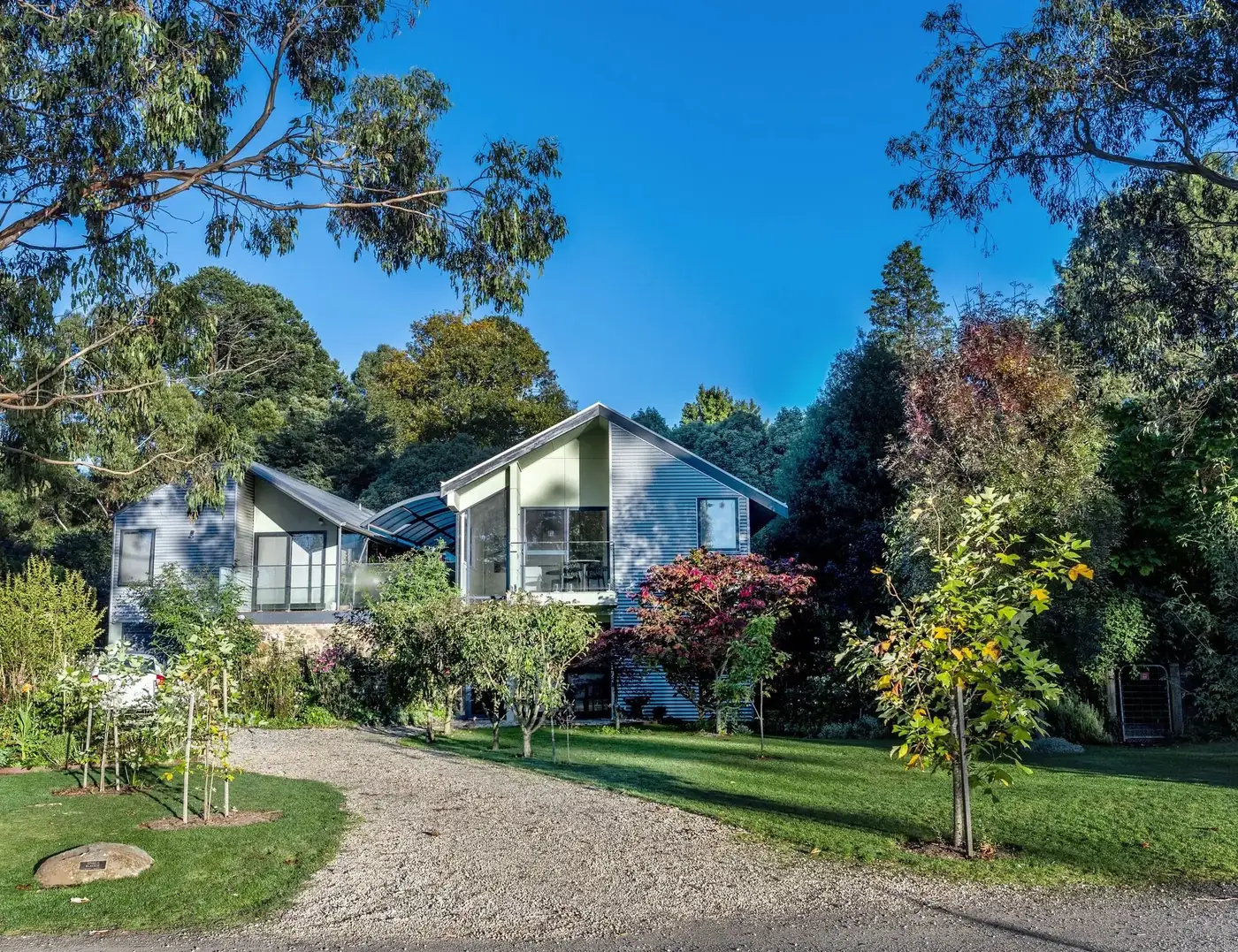 Corrugated iron villa exterior with garden beds and stone wall