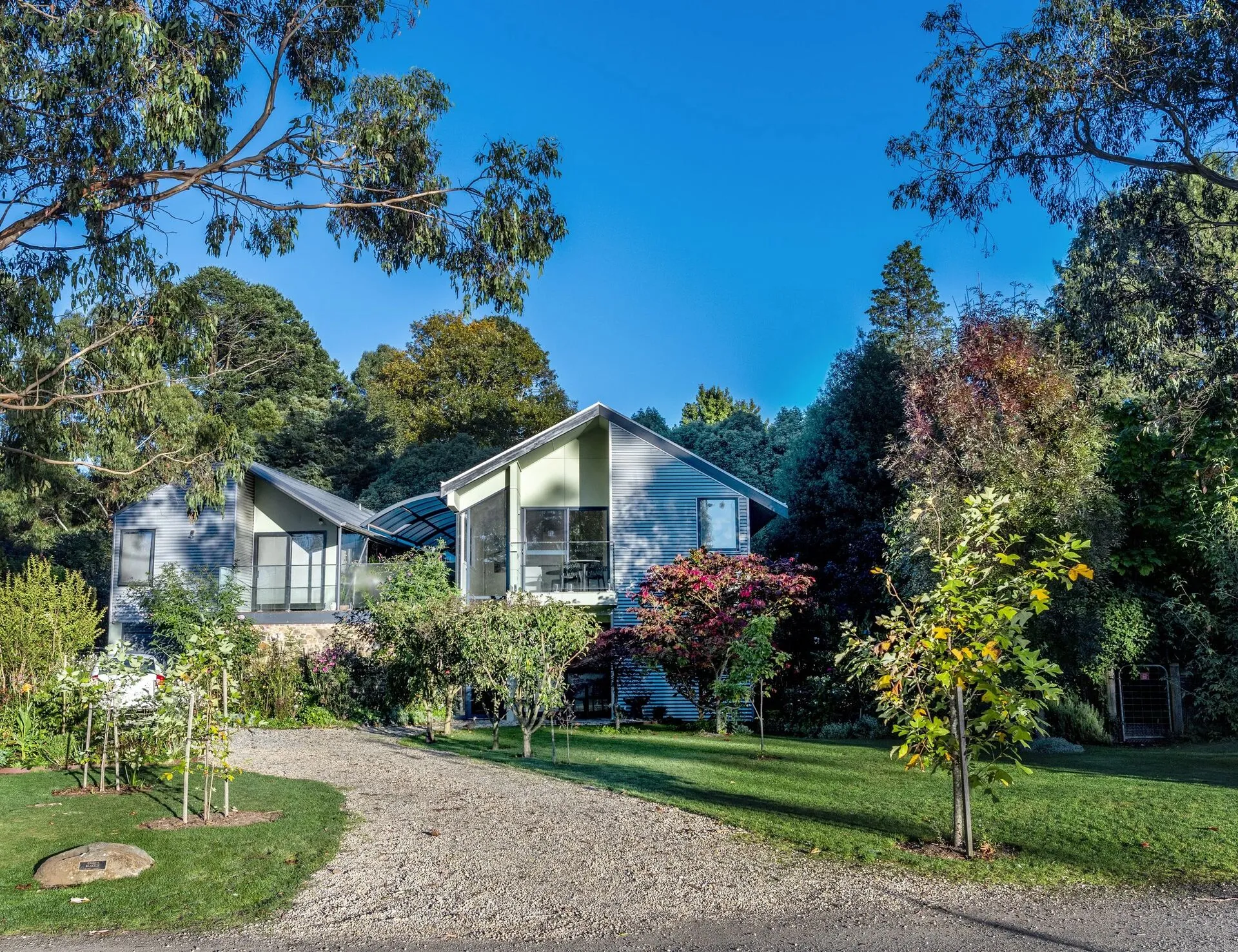Corrugated iron villa exterior with garden beds and stone wall